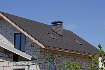 Sticker - part of a white brick house under a black tiled roof with a chimney and windows on the street against a blue sky