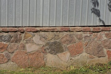 Sticker - texture of brown stone foundation and gray metal in the wall of the fence on the street