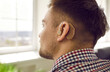 Man wearing hearing aid. Young hearing impaired patient wearing small comfortable digital or analog behind ear device. Close up side back view of man's head. Audiology and deafness treatment concept
