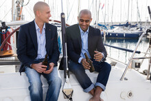 Latin American And European Businessmen Sit And Drink Beer On The Yacht In Seaport