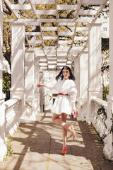 Wall Mural - beautiful woman with dark hair in elegant white clothes posing in summer park