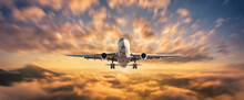 Airplane Is Flying Above The Clouds At Sunset In Summer. Landscape With Passenger Airplane, Mountains, Orange Sky. Aircraft Is Taking Off. Business Travel. Commercial Plane. Aerial View. Transport