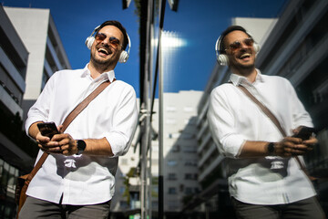 Wall Mural - young and happy business man listening music and walking in the city