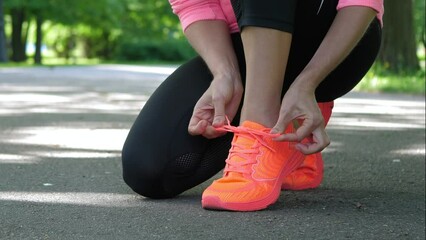 Wall Mural - fitness woman tying running shoe laces, ready for jogging in summer park. healthy lifestyle and spor
