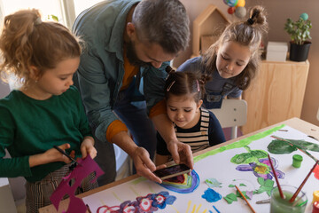 group of little kids working on project with teacher during creative art and craft class at school.