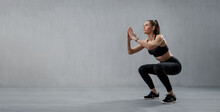 Sports Woman In Fashion Black Sport Clothes Squatting Doing Sit-ups In Gym, Over Gray Background