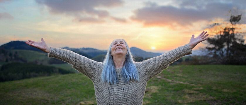 Senior woman with arms outstretched and face up at park on spring day