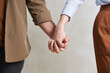 © Mediaphotos - Medium close-up studio shot of unrecognizable heterosexual young man and woman in love holding hands