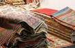 pile of many wool persian rugs with colorful geometric designs for sale in shop specializing