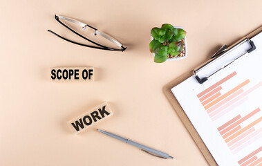 Poster - SCOPE OF WORK text on wooden block with chart and glasses, business concept