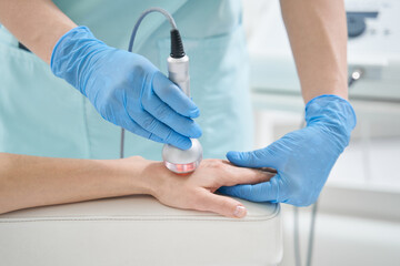 beauty professional treating vistor hand with radiofrequency therapy