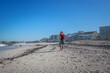 Caucasian Man walking with Jack Russell Terrier dog playing on the beach, Cape Town, South Africa