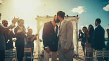 Handsome Gay Couple Walking Up The Aisle At Outdoors Wedding Ceremony Venue Near Sea. Two Happy Men In Love Share Their Big Day With Diverse Multiethnic Friends. Authentic LGBTQ Relationship Goals.