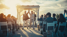 Handsome Gay Couple Exchange Rings And Kiss At Outdoors Wedding Ceremony Venue Near The Sea. Two Happy Men In Love Share Their Big Day With Diverse Multiethnic Friends. LGBTQ Relationship Goals.