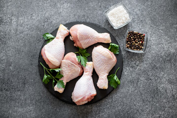 Wall Mural - raw chicken legs with spices on a stone background