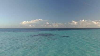 Wall Mural - camera moving towards sunset clouds over indian ocean and shallow blue tropical water at maldives
