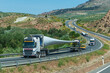 Convoy of trucks transporting wind turbine blades, circulating on the highway.