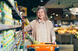 © Liubomir - Portrait of a senior gray-haired woman in a supermarket in the grocery store chooses groceries, a pensioner looks at the camera and smiles
