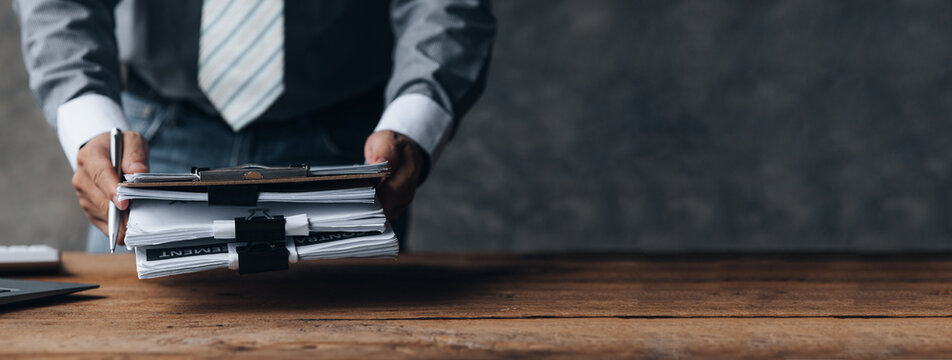 businessman holding a pile of company financial documents, he is checking company finances before at