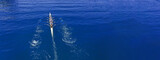 Aerial drone top ultra wide panoramic view of sport canoe rowing synchronous team of athletes competing in deep blue sea