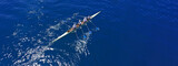 Aerial drone top ultra wide panoramic view of sport canoe rowing synchronous team of athletes competing in deep blue sea