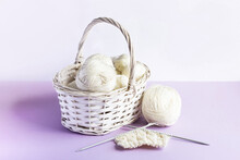 White Balls Of Thread In A Basket On A Lilac Background For Knitting Warm Clothes And Hobbies Needlework