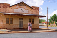 Street View Of Faded Pink Petrol Pump In Front Of Old Deserted Building