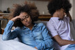 © fizkes - Disappointed tired Black teen girl ignoring offended boyfriend, thinking over conflict, arguing, bad relationships, psychological manipulation, abuse, keeping distance on couch