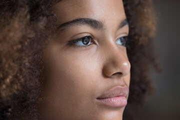 Looking forward. Close up face teen Afro American lady staring far away. Brown eyes of serious young woman wearing modern soft contact lenses. Female patient enjoy good eyesight after laser correction