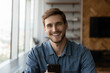 Leinwandbild Motiv Head shot of happy young millennial man holding smartphone, looking at camera, smiling, laughing. Portrait of positive customer, smartphone user satisfied with online app, virtual service work