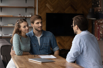 Millennial couple of clients meeting with real estate agent, realtor, broker, discussing house buying, apartment rent, mortgage bank terms. Lawyer giving consultation to customers. Property purchase