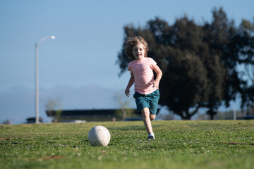 Wall Mural - Soccer kid. Kids play football on outdoor stadium field. Little boy kicking ball. School football sports club. Kids training soccer.