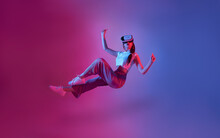 Amazed Young Woman Using A Virtual Reality Headset Playing Video Games Trying To Touch Something With Hand Floating In Mid-air.