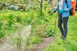 © Valerii Honcharuk - Woman with backpack garden spray gun under pressure handling bushes roses