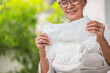 Happy smiling asian senior woman showing disposable diaper for adult,looking at nappy pamper with satisfaction,old elderly patient with urinary incontinence,consumer goods,health care concept