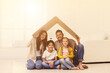 © New Africa - Happy family sitting under cardboard roof at home. Insurance concept