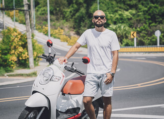 Wall Mural - Stylish young man with his motorbike on the road