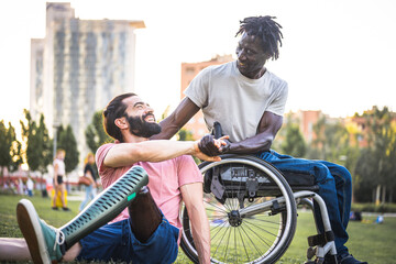 Two friends who have different physical disabilities greet each other at the park, adult African man in wheelchair shaking hands with his Hispanic friend with an artificial leg