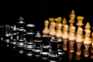 Close up of Chess pieces on a reflective mirror board surface with black background