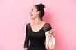 Young caucasian woman practicing ballet isolated on pink background laughing in lateral position