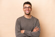 © luismolinero - Young Brazilian man isolated on beige background keeping the arms crossed in frontal position