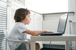 © Hanna - Boy sits at the table, uses laptop, typing on a keyboard, looks at the screen. Child does homework lesson, plays video game, study IT course. Home distance online education concept. Smart technology