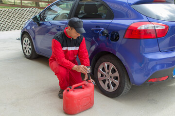 Image of a mechanic in overalls as he pours an additive into the tank of a car. Reference to expensive fuel