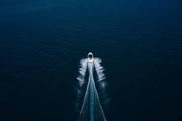 Wall Mural - Large white boat fast movement on blue water aerial view. Drone view of a boat sailing. Top view of a white boat sailing to the blue sea. Motor boat in the sea. Travel - image.