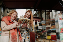 A Grandmother And Granddaughter Choosing Books At Bookstore.