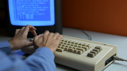 Man in a blue shirt is programming on an old computer