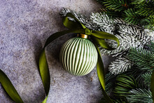 Close-up Of A Green Ceramic Christmas Bauble On A Table With Fir Branches