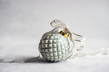 Close-up Of A Grey Ceramic Christmas Bauble Tied With Ribbon On A Table