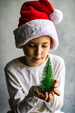 Boy Wearing A Santa Hat Holding A Christmas Tree Ornament