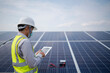 © RooM The Agency - Engineer with a digital tablet standing next to solar panels at a solar powered station, Thailand